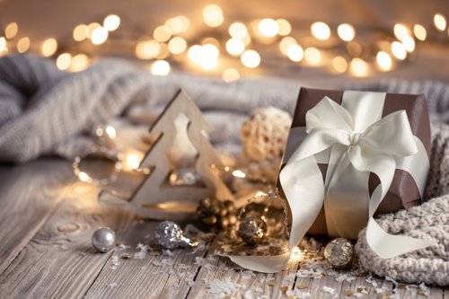 Mesa con regalos envueltos en papeles coloridos y adornos navideños, esferas y luces, creando un ambiente cálido y festivo de Navidad.