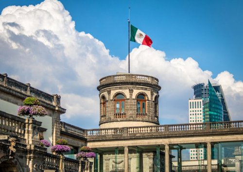 Castillo de Chapultepec en la Ciudad de México con la bandera nacional ondeando majestuosamente en la cima, símbolo de historia y orgullo mexicano.
