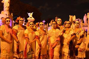 Personas con rostros de calaveras y trajes tradicionales, celebrando el Día de Muertos en México con orgullo y respeto por sus antepasados